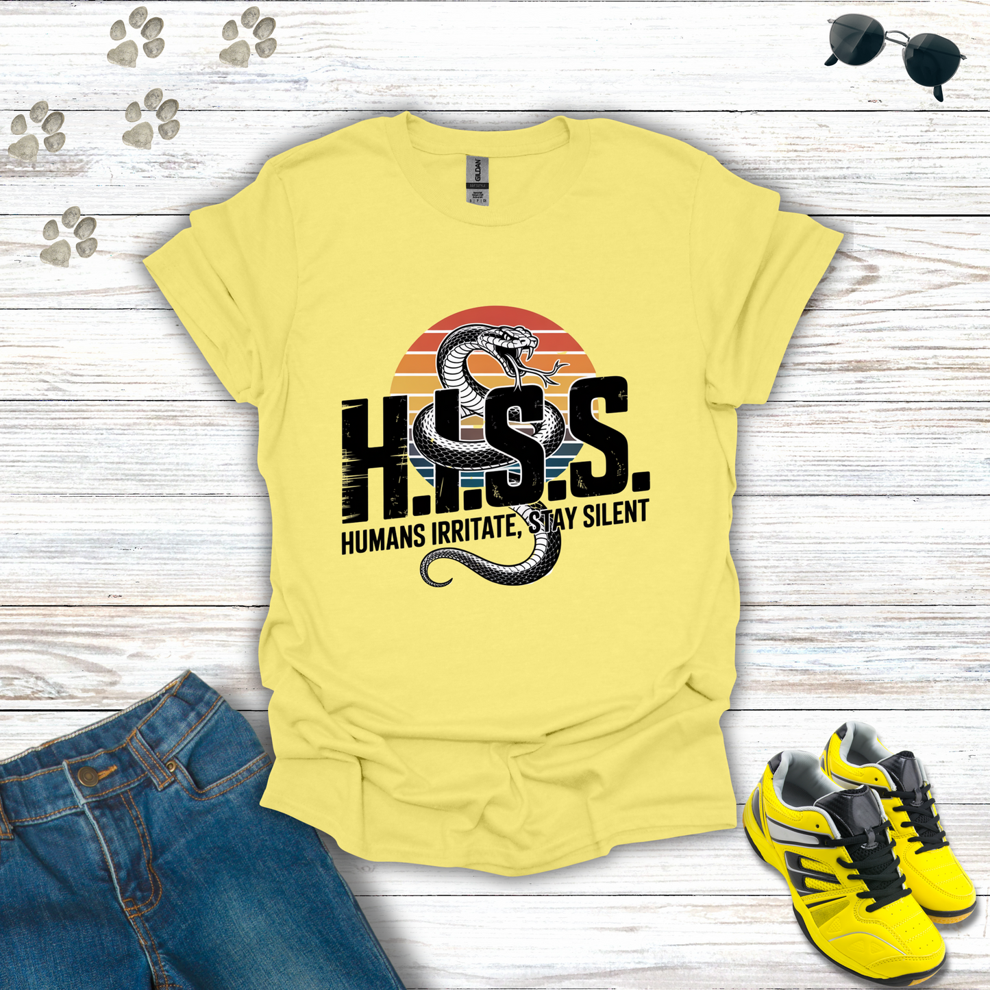 Yellow t-shirt with snake graphic and text on a wooden surface with jeans and sneakers.