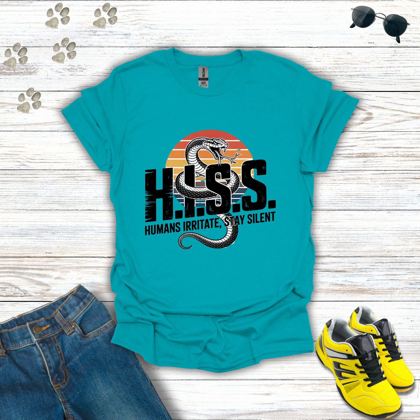 Turquoise t-shirt with snake graphic and text on a wooden surface with jeans and sneakers.