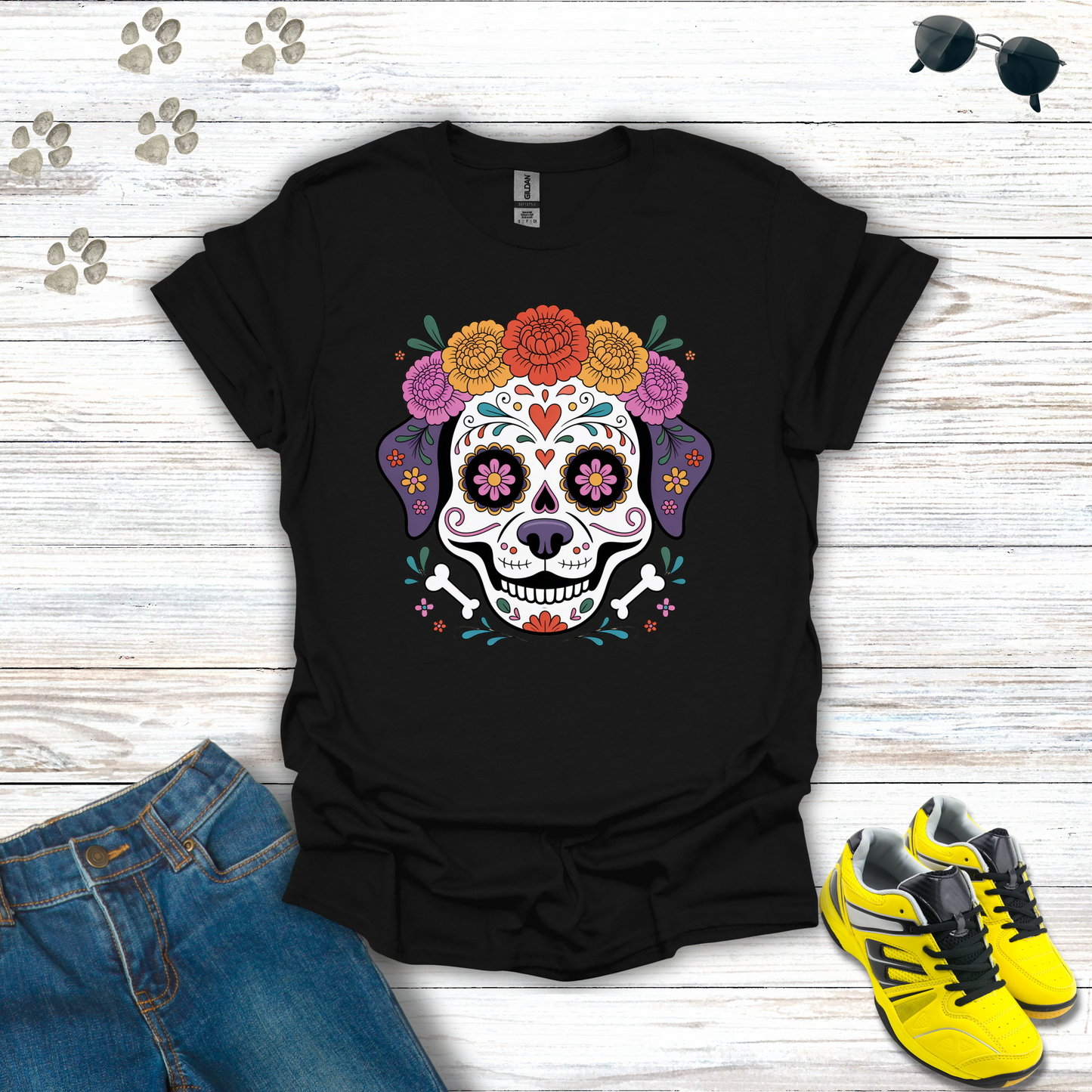 Black t-shirt with colorful skull design on a wooden surface with jeans and sneakers.