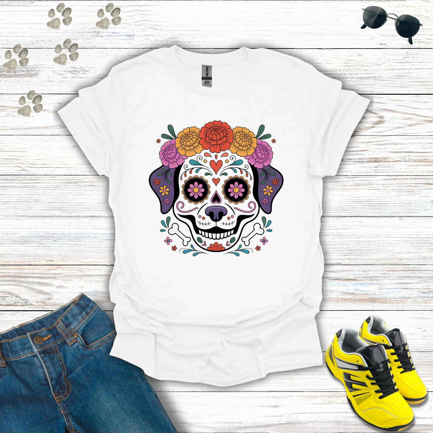 White t-shirt with a colorful skull design on a wooden surface with jeans and shoes.
