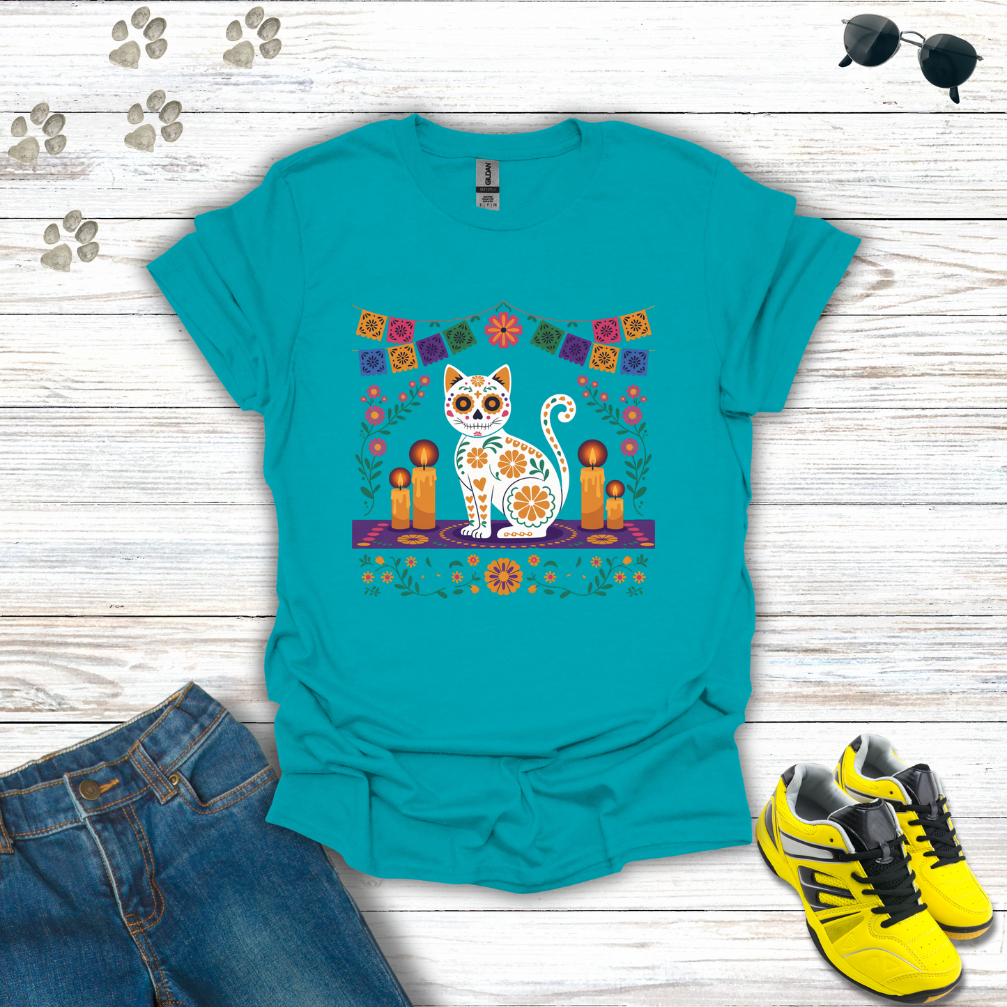 Turquoise t-shirt with a cat design on a wooden surface with jeans and shoes.