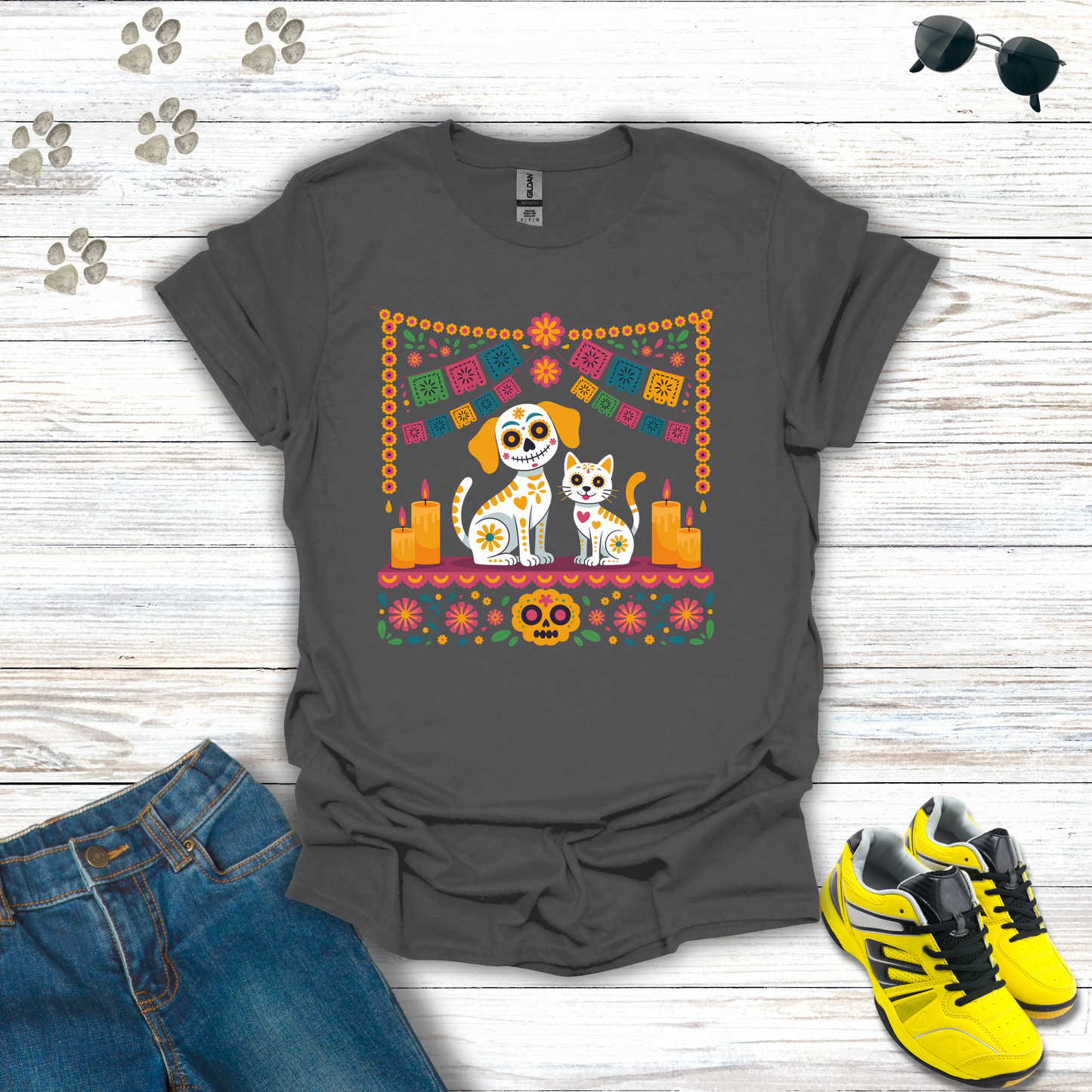 Charcoal t-shirt with a colorful graphic of a dog and cat, surrounded by flowers and skulls, on a wooden surface with jeans and shoes.