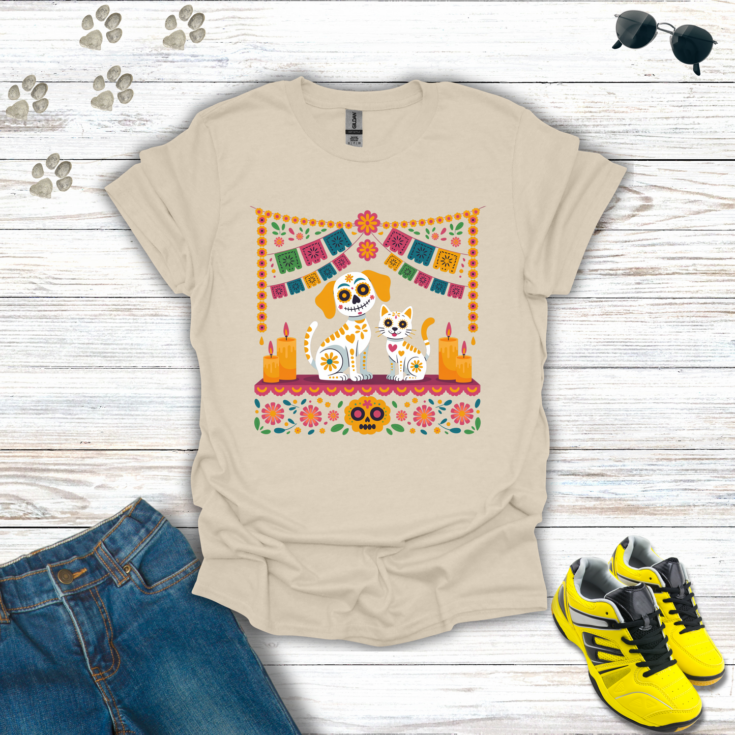 Natural t-shirt with a colorful graphic design featuring a dog and cat, placed on a wooden surface with jeans and shoes.