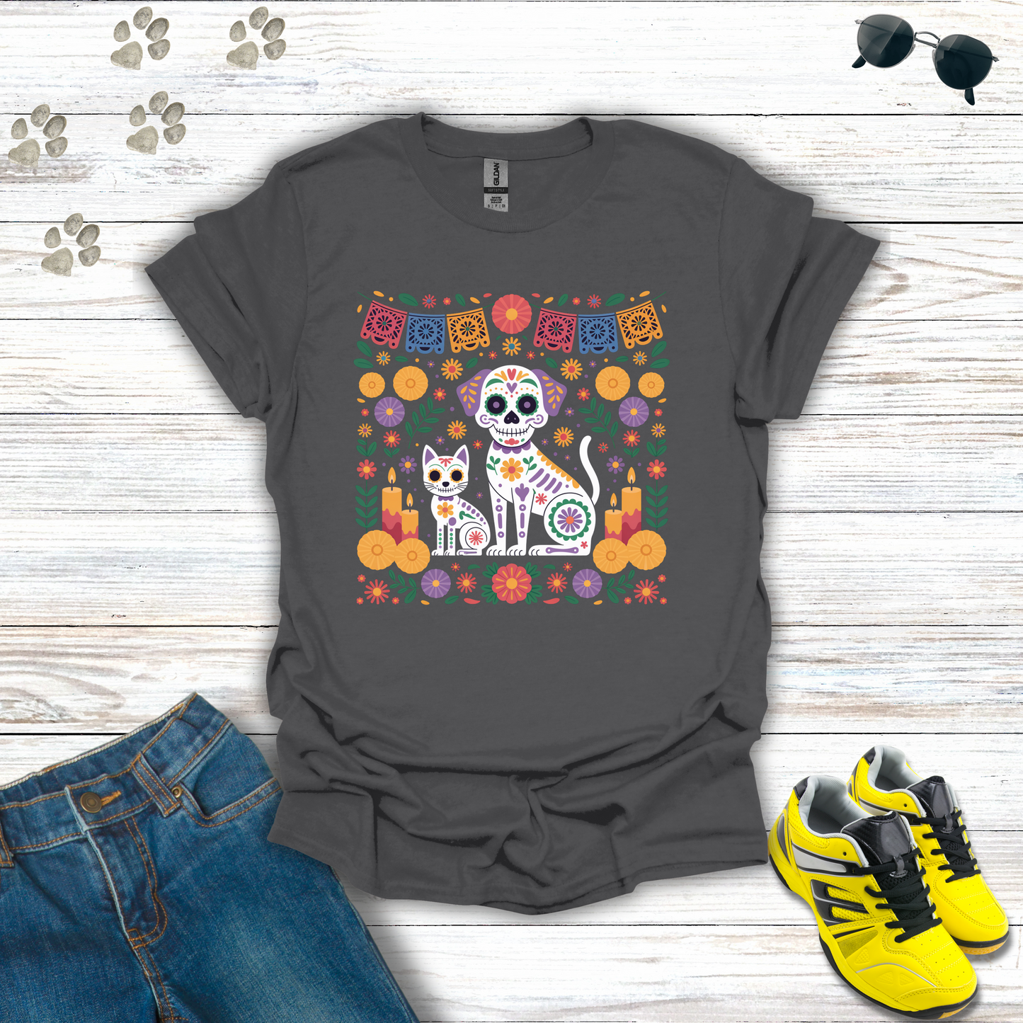 Charcoal t-shirt with a colorful cat and skull design on a wooden surface with jeans and sneakers.