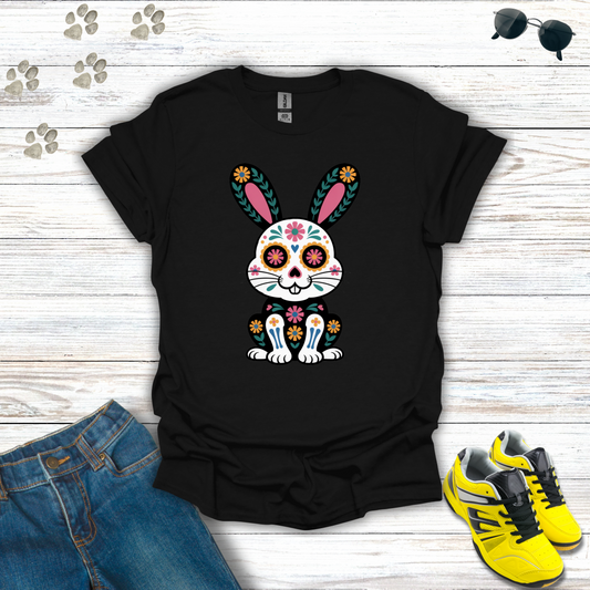 Black t-shirt with colorful bunny design on a wooden surface with jeans and sneakers.