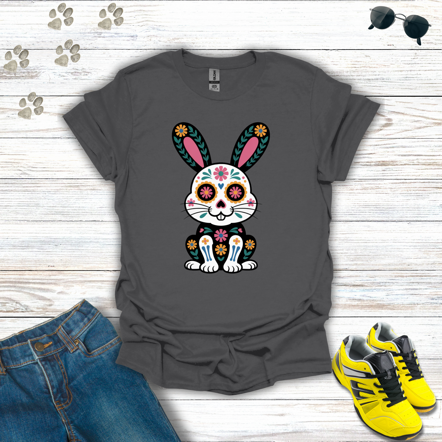 Charcoal t-shirt with a colorful bunny design on a wooden surface with jeans and sneakers.