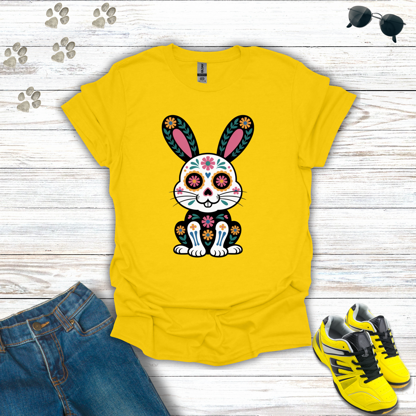 Daisy t-shirt with a colorful bunny design on a wooden surface with jeans and shoes.