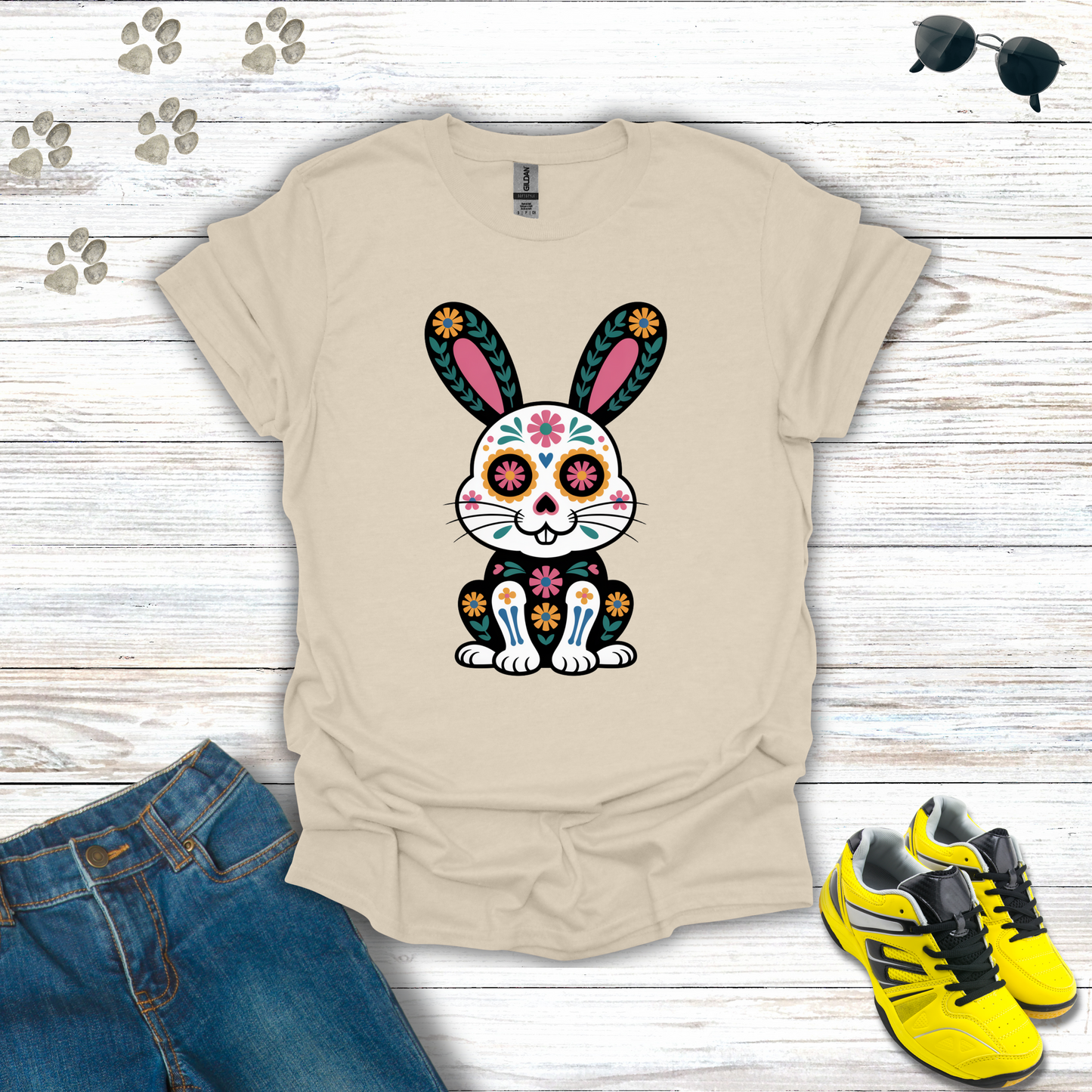 Natural t-shirt with a colorful bunny design on a wooden surface with jeans and shoes.
