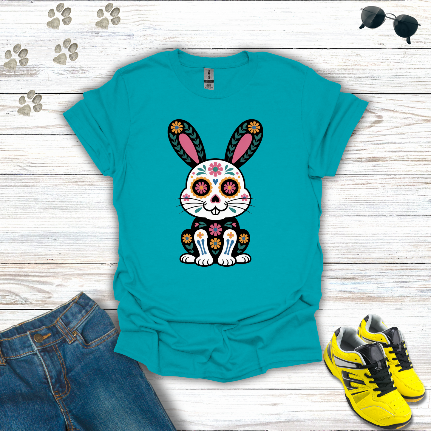 Tropical Blue t-shirt with a colorful bunny design on a wooden surface with jeans and shoes.