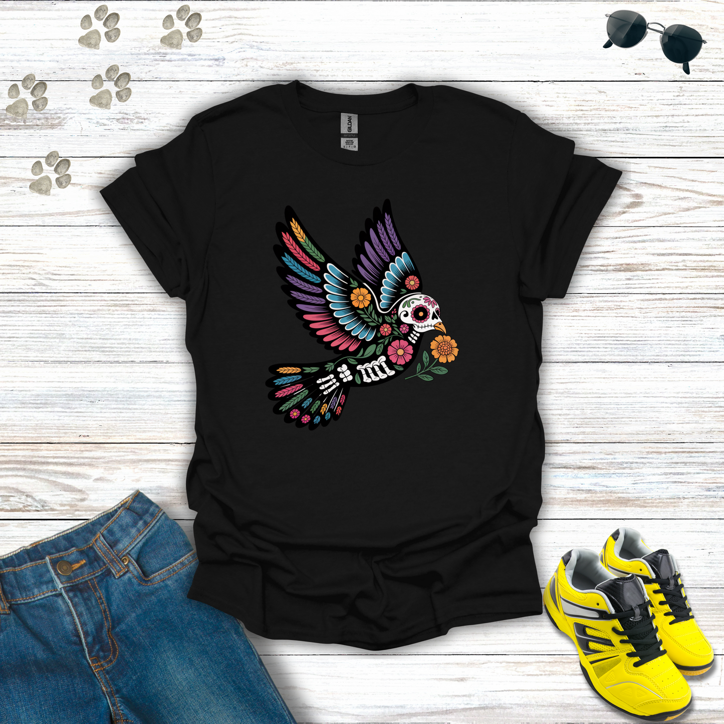 Black t-shirt with colorful skeleton design on a wooden surface with jeans and sneakers.