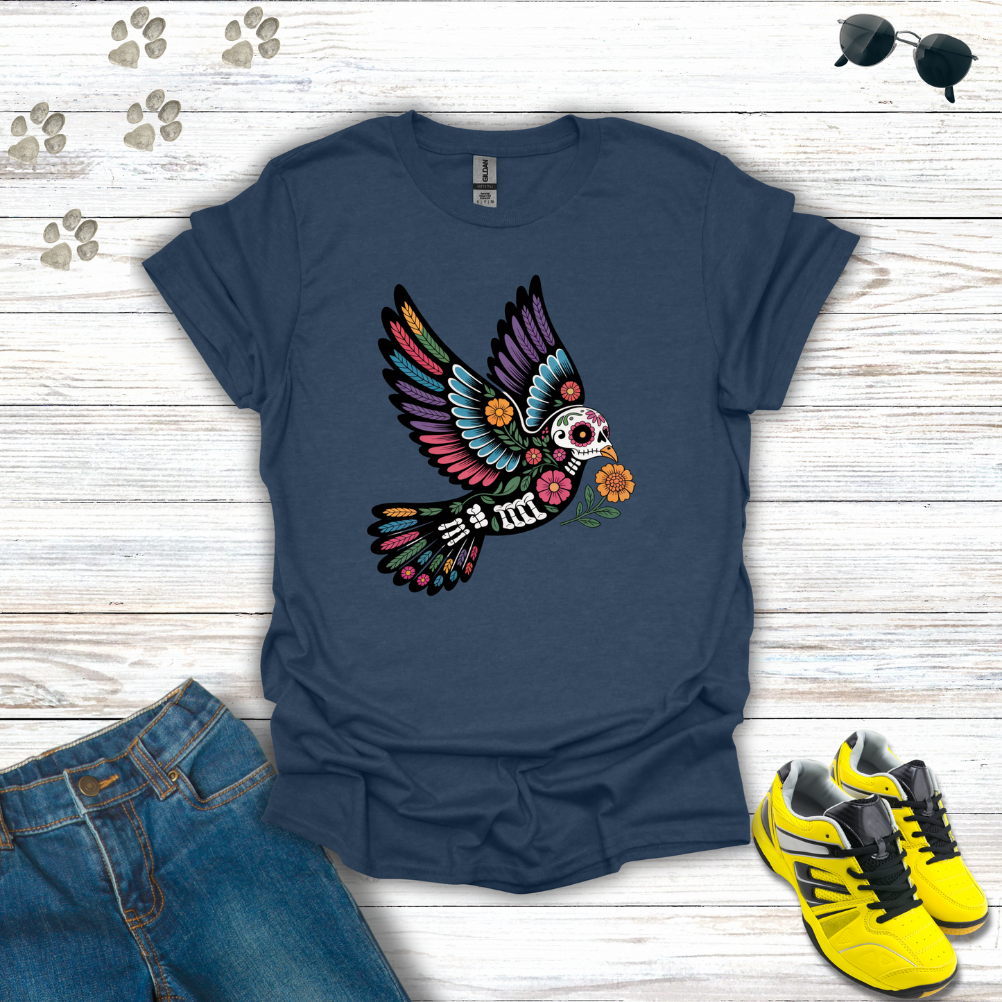 Heather Navy t-shirt with colorful skeleton dove design on a wooden surface with jeans and sneakers.