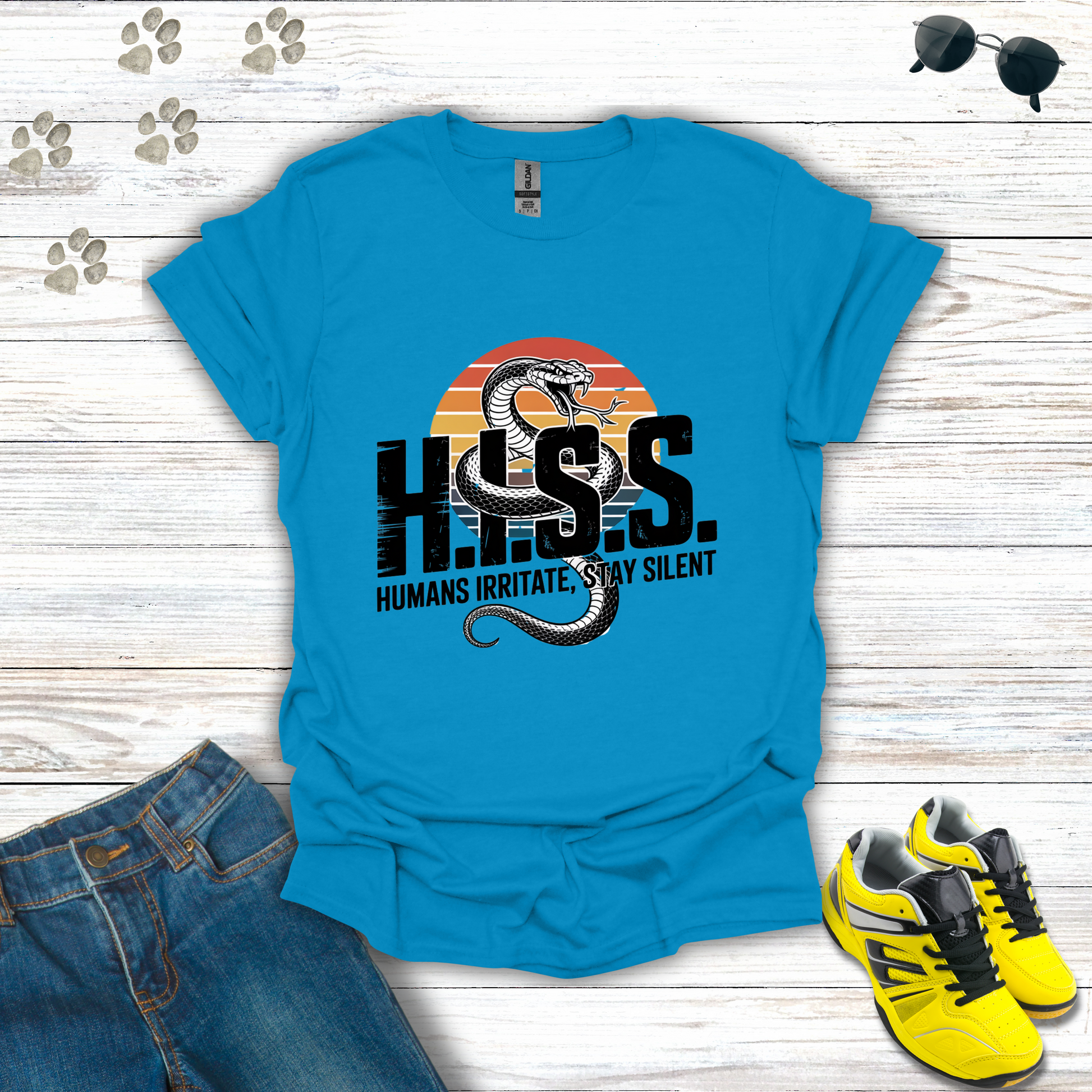 Blue t-shirt with snake graphic and text on a wooden surface with jeans and sneakers.