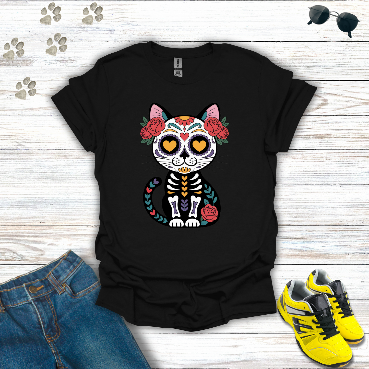 Black t-shirt with a colorful cat skeleton design on a wooden surface with jeans and sneakers.