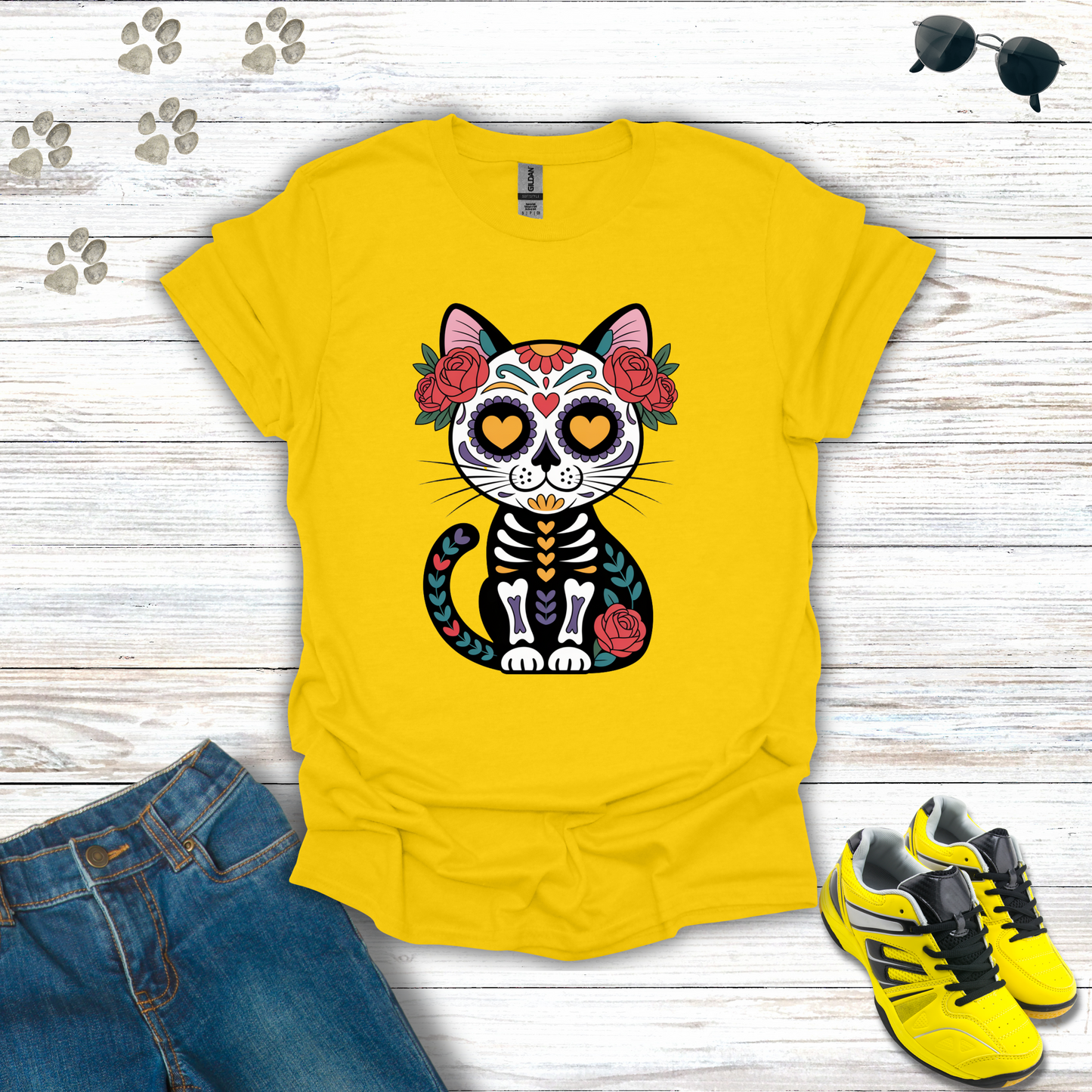Daisy t-shirt with a cat skeleton design on a wooden surface with jeans and shoes.