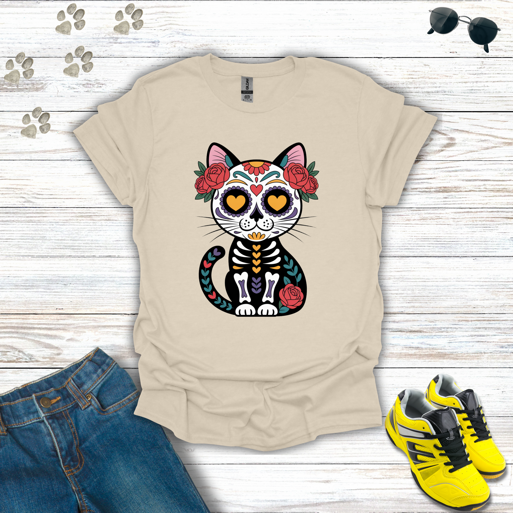 Natural t-shirt with a colorful cat skeleton design on a wooden surface with jeans and sneakers.
