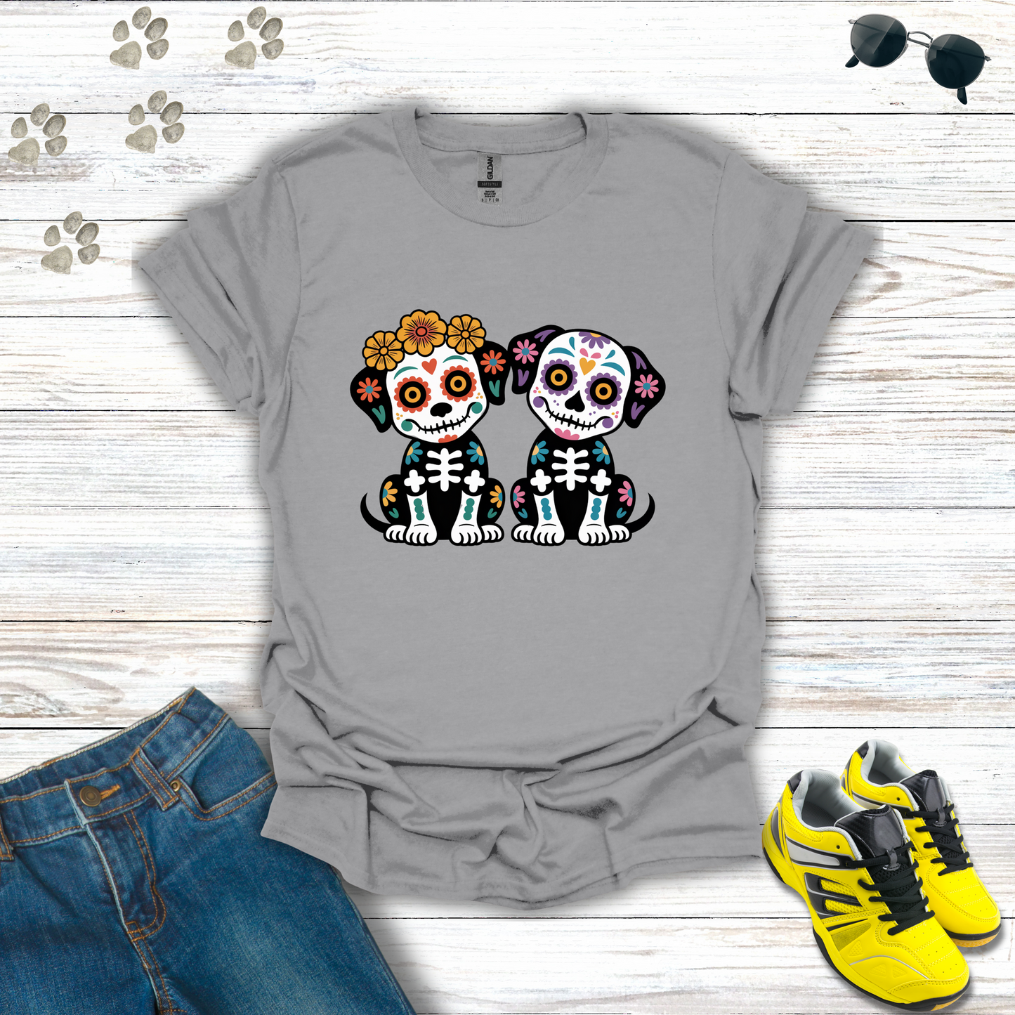 Sport Gray t-shirt with skull design of two dogs, placed on a wooden surface with jeans and sneakers around.