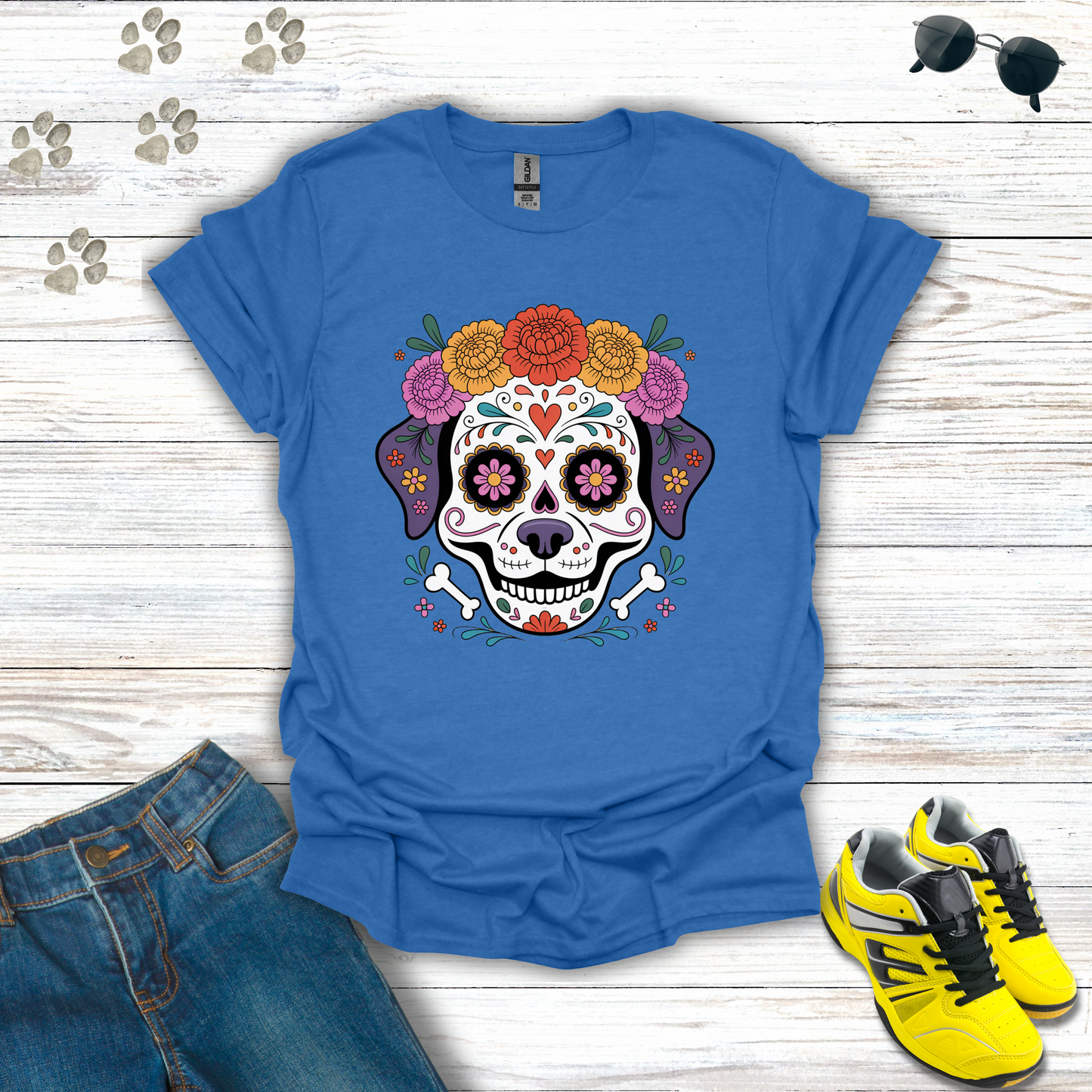 Heather Royal t-shirt with a colorful skull design on a wooden surface with jeans and sneakers.