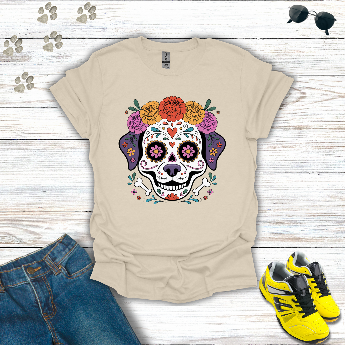Natural t-shirt with a colorful skull design on a wooden surface with jeans and sneakers.