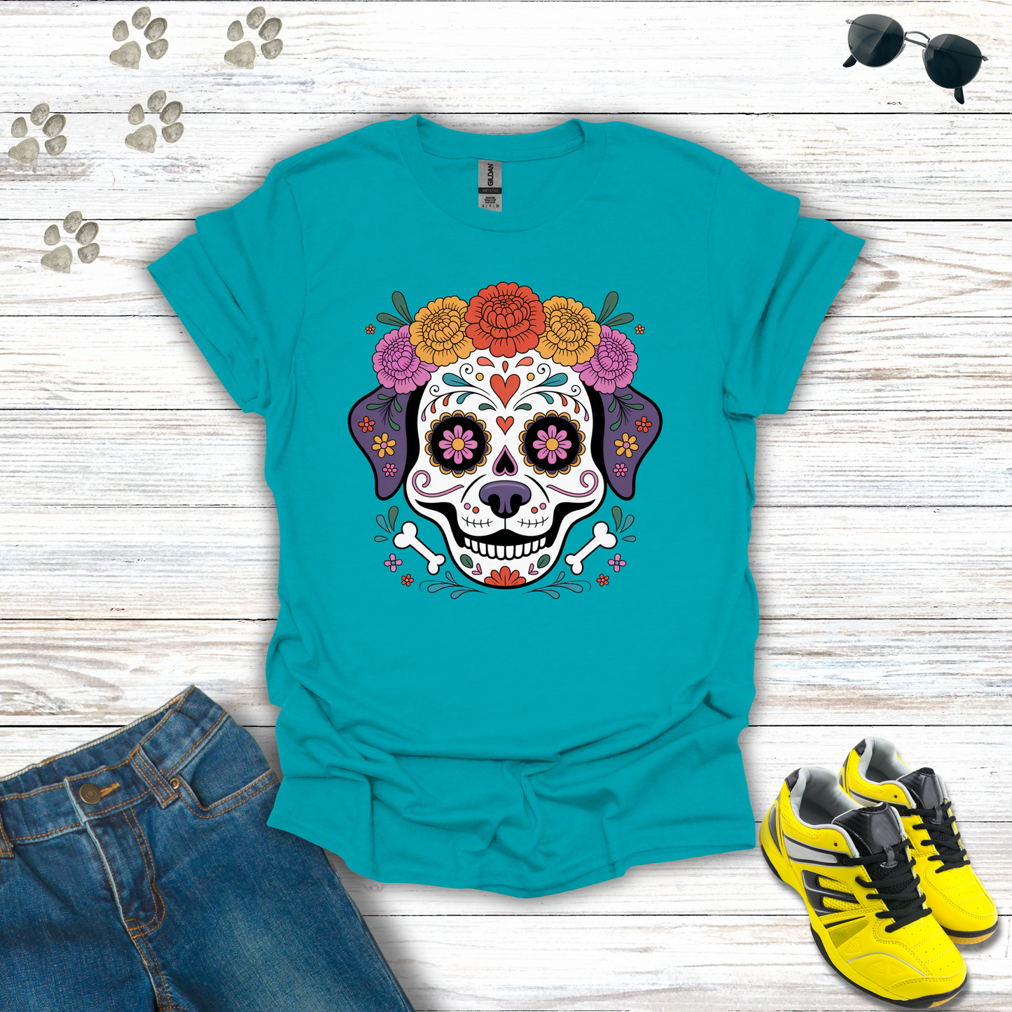 Tropical Blue t-shirt with a colorful skull design on a wooden surface with jeans and sneakers.