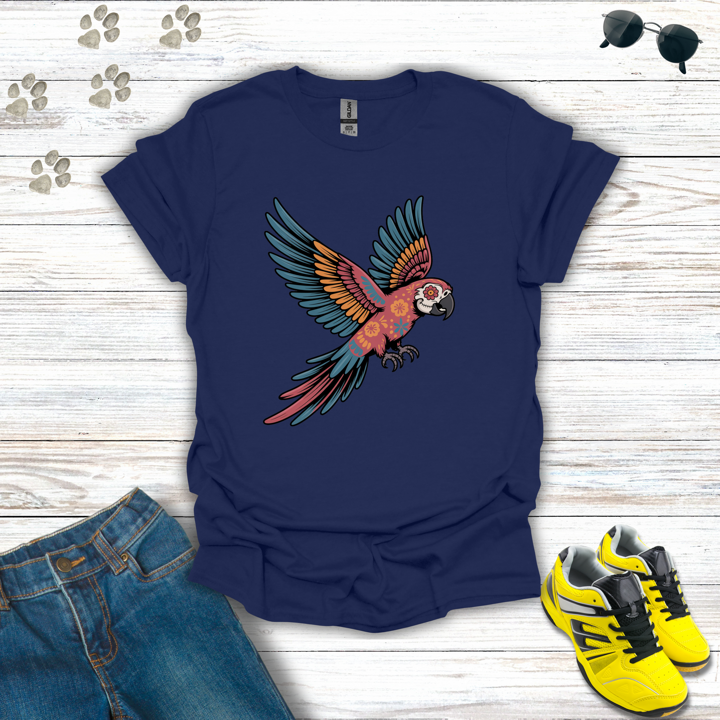 Navy blue t-shirt with a parrot design on a wooden surface with jeans and sneakers.