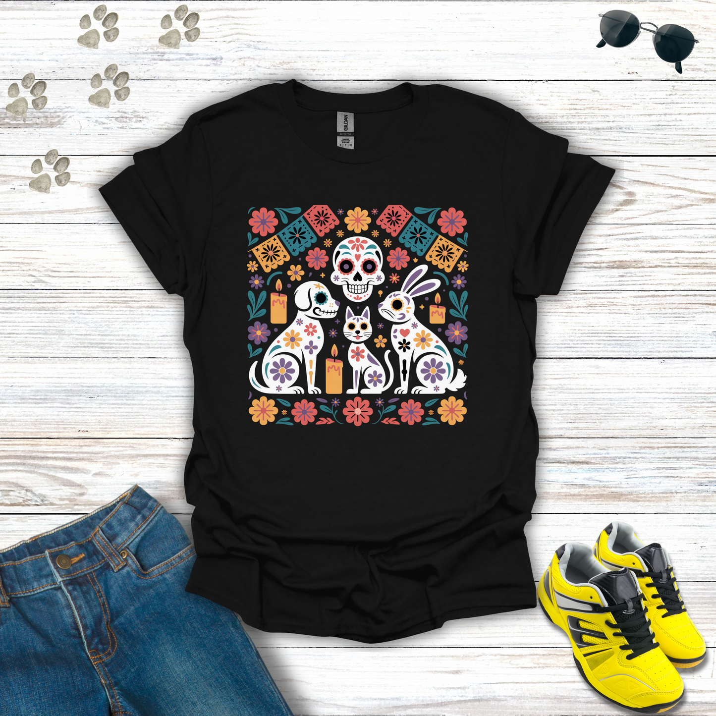 Black t-shirt with colorful graphic design featuring animals and flowers on a wooden surface with jeans and sneakers.
