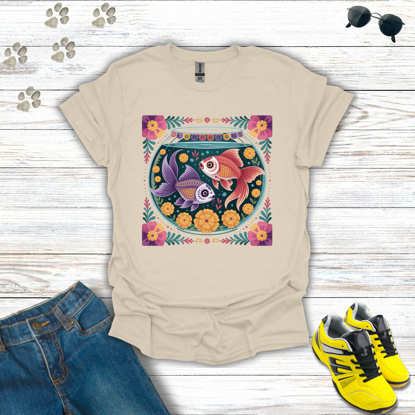 Natural t-shirt with fish bowl design on a wooden surface with jeans and sneakers.
