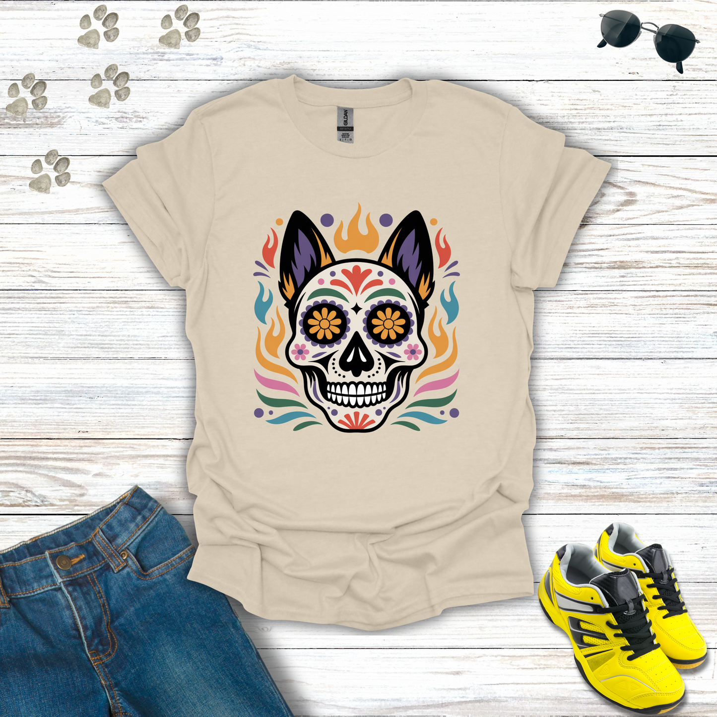 Natural t-shirt with colorful skull design on a wooden surface with jeans and sneakers.