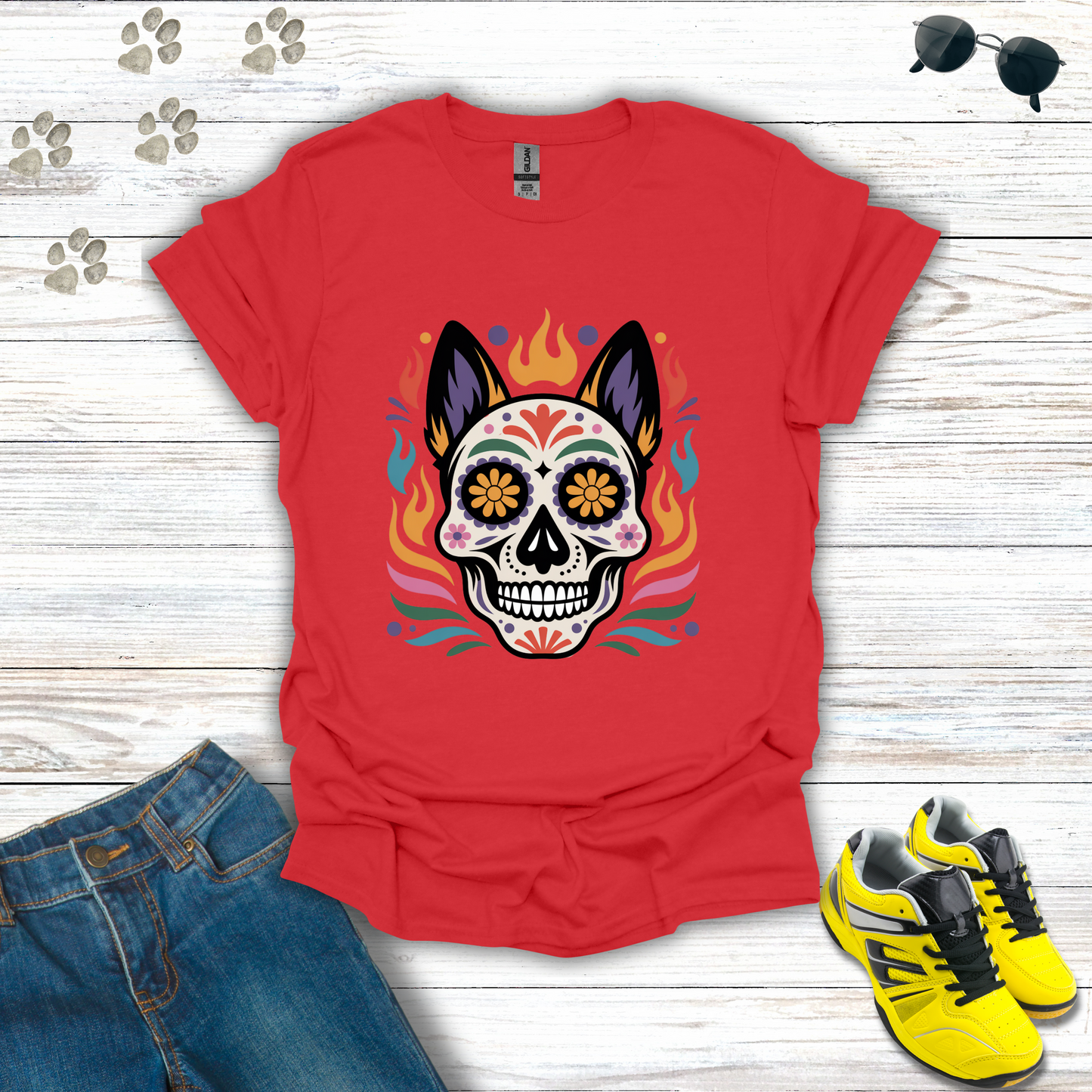Red t-shirt with a colorful skull design on a wooden surface with jeans and sneakers.