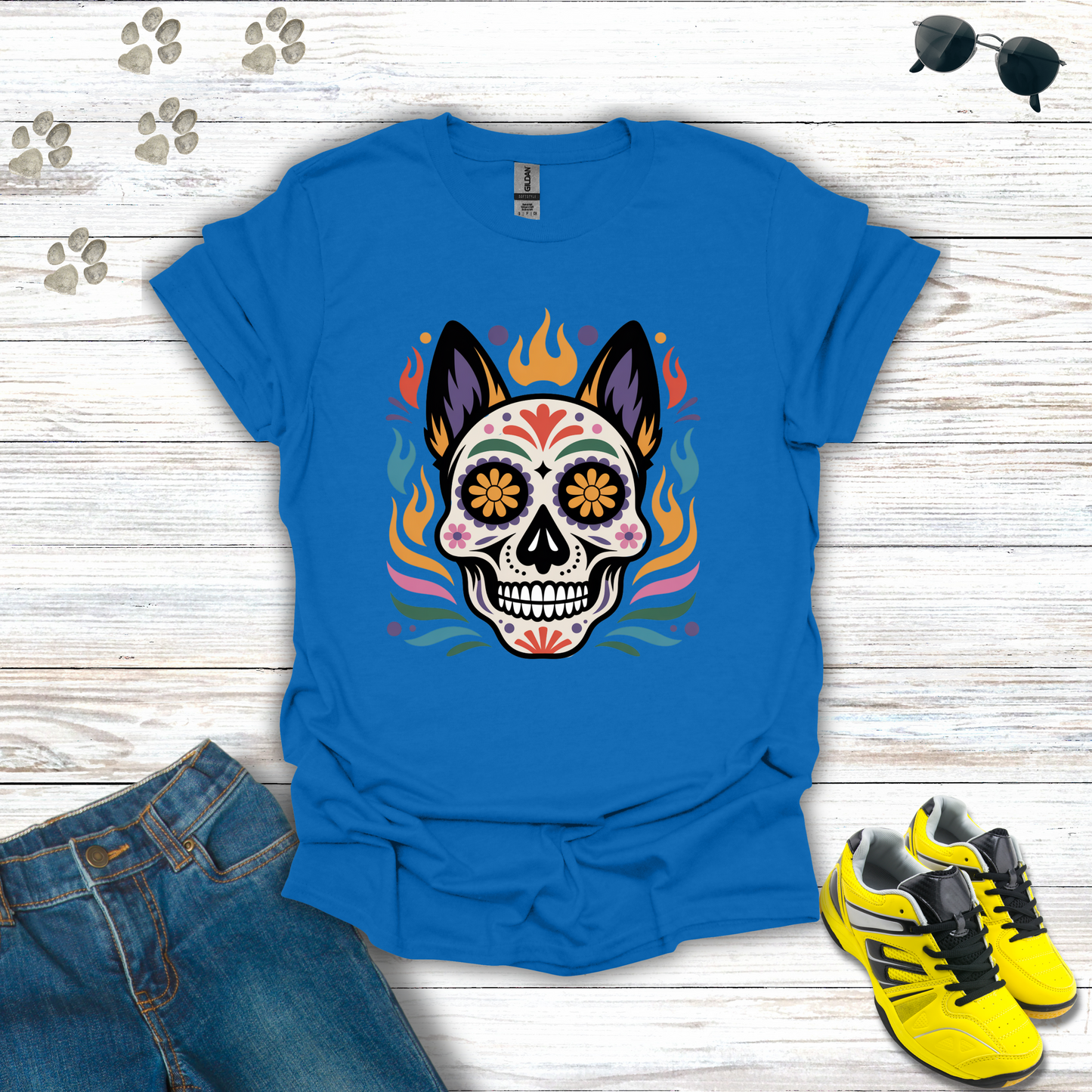 Royal t-shirt with a colorful skull design on a wooden surface with jeans and sneakers.