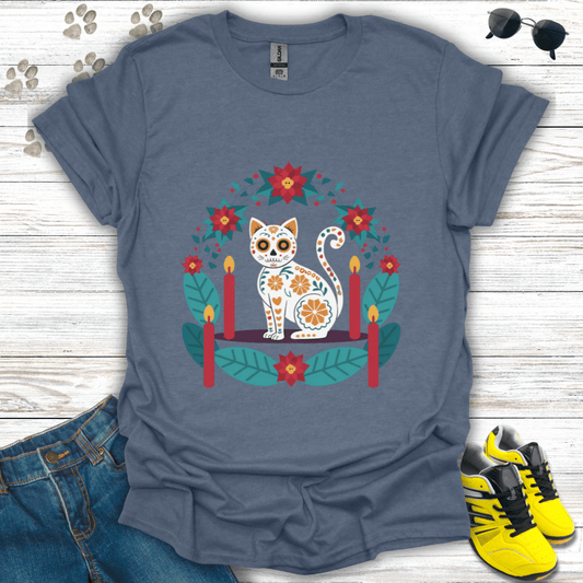 Christmas Sugar Skull Cat T-Shirt on heather indigo Gildan tee showing a white sugar-skull cat surrounded by teal leaves and red poinsettias — vibrant Christmas folk-art design.